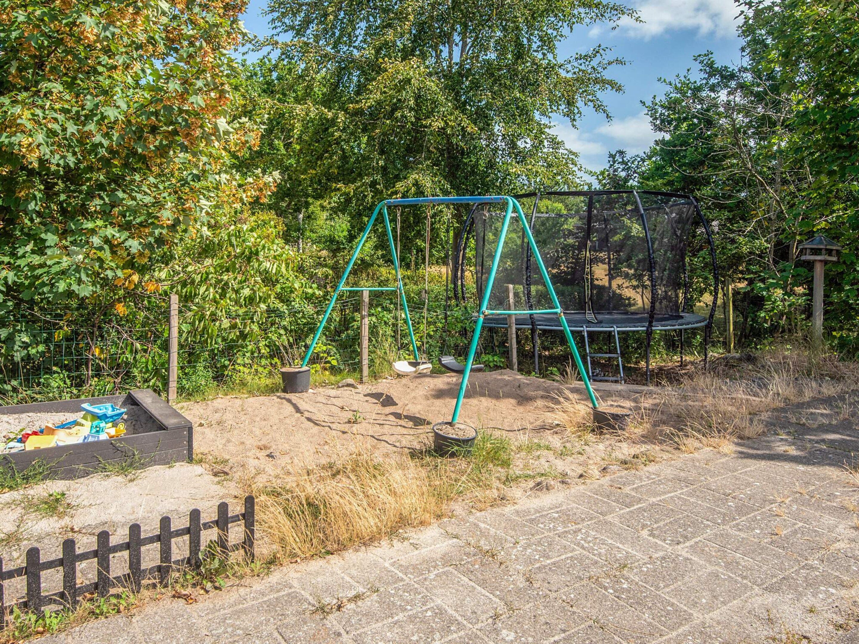 Ein Spielplatz mit Schaukeln und Trampolin.