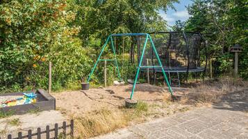 Ein Spielplatz mit Schaukeln und Trampolin.