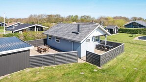 Une maison moderne avec un toit en pente, une cour arrière clôturée et un petit espace patio.