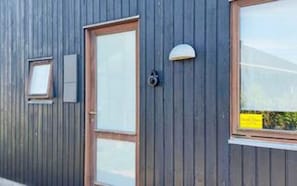 A building with a wooden door, a window, and a small light fixture on the wall. - 5 Star Holiday Home in Ulfborg (Ulfborg)