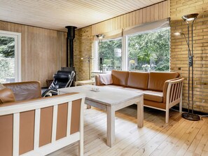 A cozy living room with a sofa, a chair, a table, and a fireplace. - 4 Star Holiday Home in Vaeggerlose (Vaeggerlose)