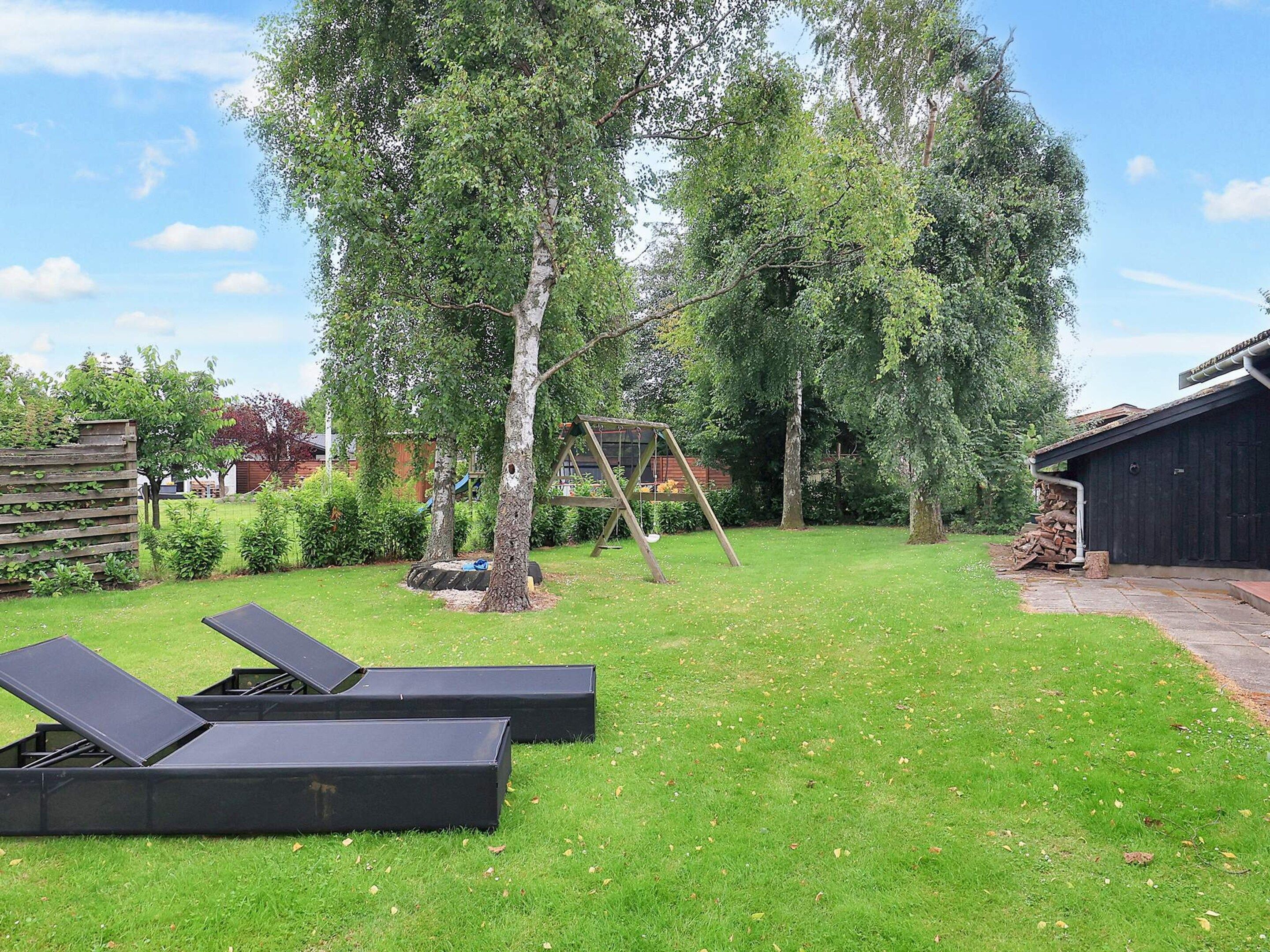 A backyard with a swing set, a wooden fence, and a shed.