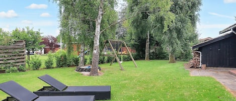 A backyard with a swing set, a wooden fence, and a shed.