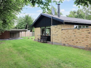 A brick building with a sloped roof, a satellite dish, and a bench outside. - 4 Star Holiday Home in Vaeggerlose (Vaeggerlose)