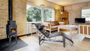 Ett modernt vardagsrum med en öppen spis, en lädersoffa, en tv och en matplats.