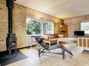 A modern living room with a fireplace, a leather sofa, a TV, and a dining area. - 4 Star Holiday Home in Vaeggerlose (Vaeggerlose)
