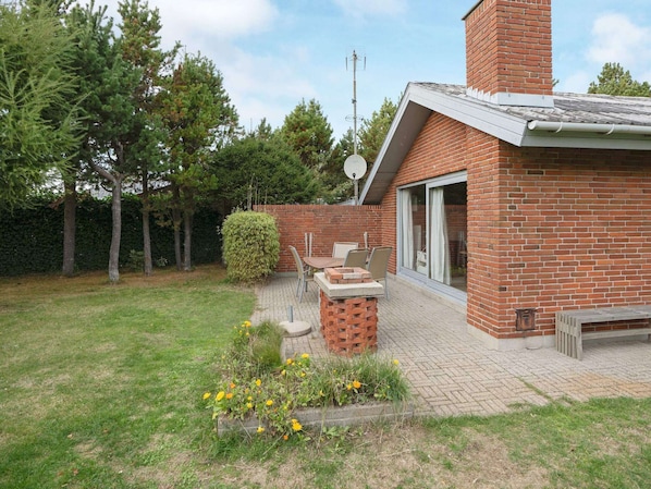 Une maison en briques avec un patio, une cheminée et une antenne parabolique.