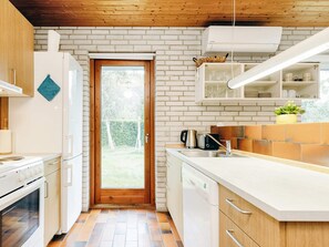 A modern kitchen with white cabinetry, a wooden door, and a view of the outdoors. - 4 Person Holiday Home in Vaeggerlose (Vaeggerlose)