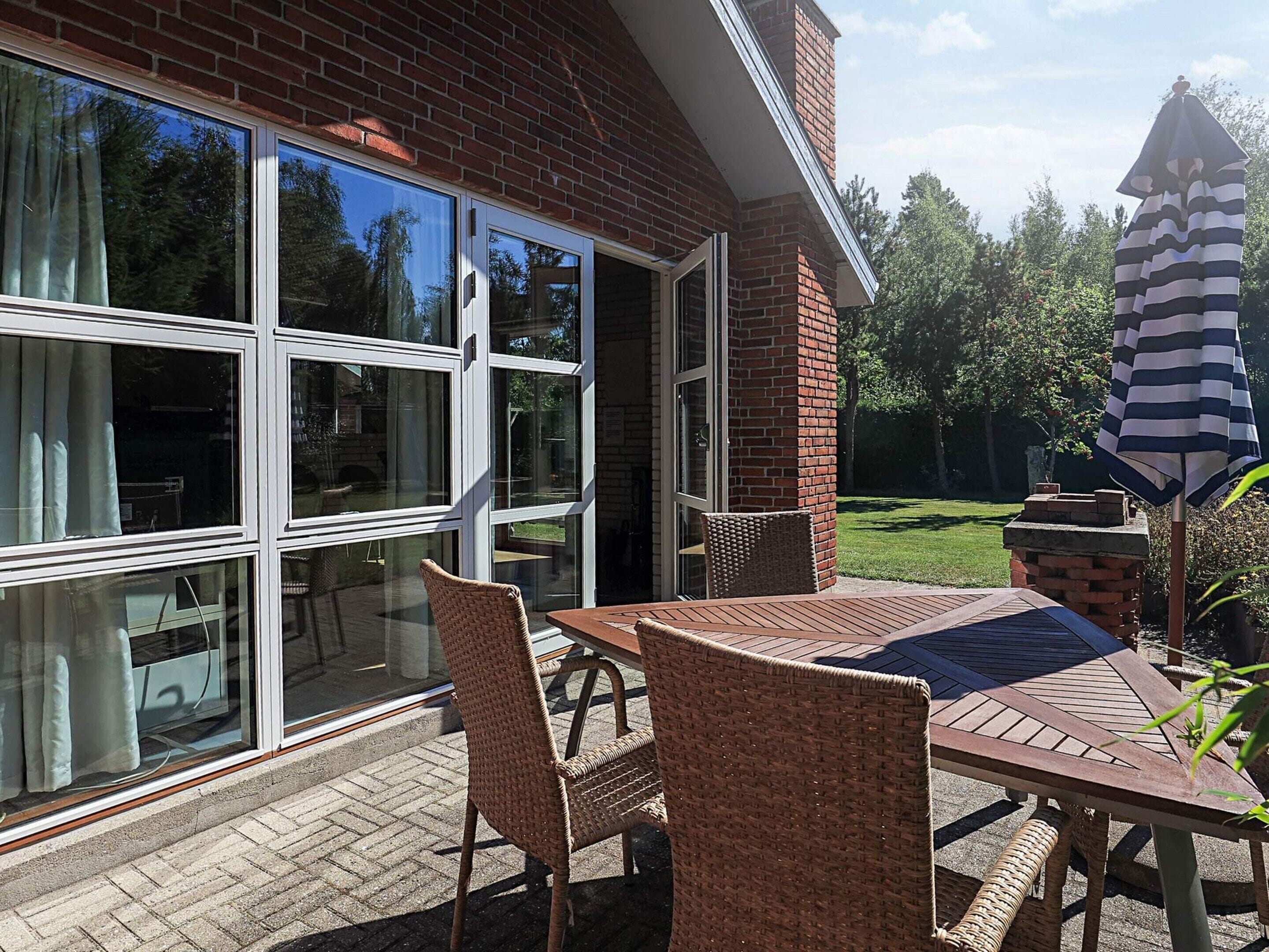 A patio with wicker furniture, a brick wall, and a large window.