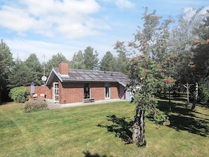 A single-story brick house with a front porch, a chimney, and a small attached garage. - 4 Person Holiday Home in Vaeggerlose (Vaeggerlose)