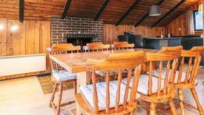 A rustic dining area with a brick fireplace, wooden chairs, and a long table. - 4 Star Holiday Home in Rodby (Rodby)