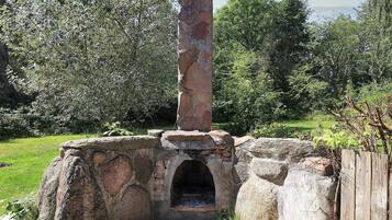 Una edificación de piedra con chimenea, rodeada de follaje.