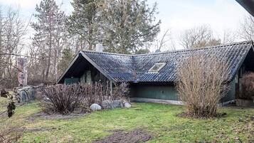 Eine rustikale Holzhütte mit geneigtem Dach, einem kleinen Fenster und einem Steinsschornstein.