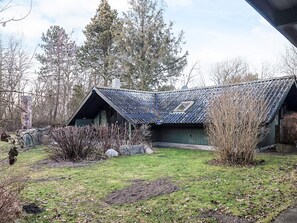 A rustic cabin with a sloped roof, a small window, and a stone chimney. - 4 Star Holiday Home in Rodby (Rodby)