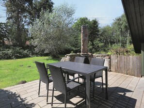 A patio with a table and chairs, surrounded by a stone wall and a wooden fence. - 4 Star Holiday Home in Rodby (Rodby)
