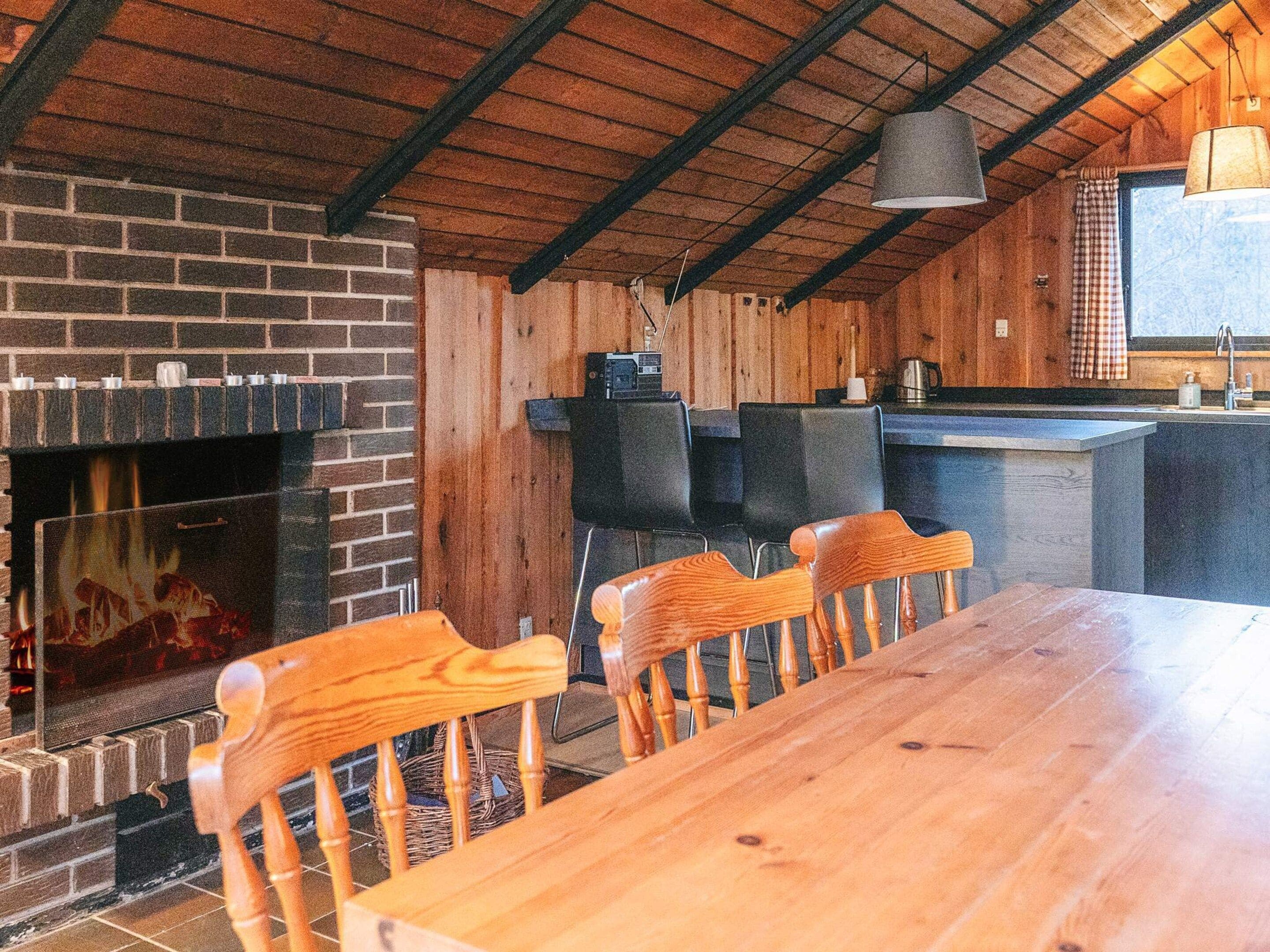 Ein rustikales Interieur mit Kamin aus Ziegelsteinen, einem Holzespeisetisch und Stühlen.