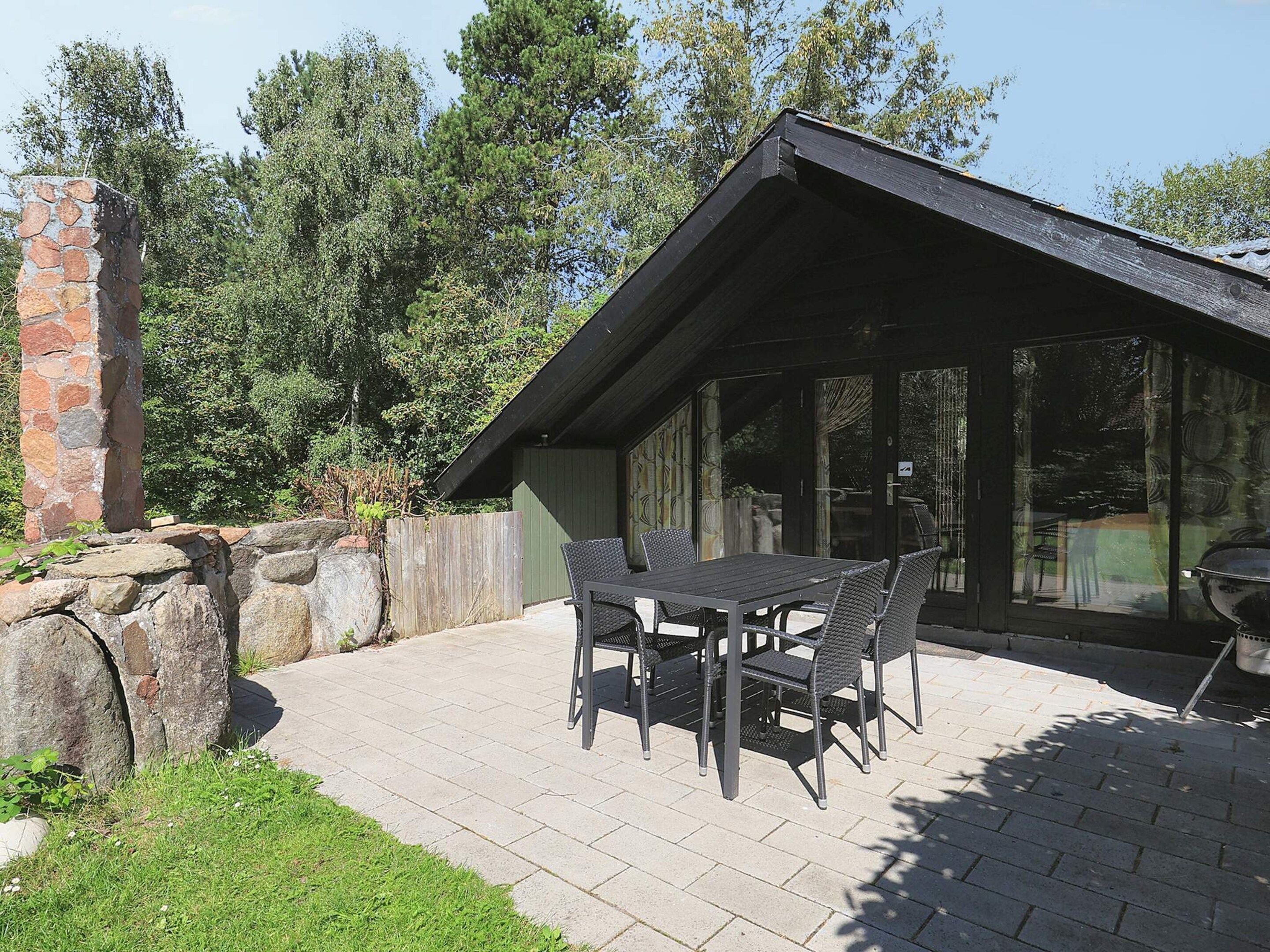 Een terras met een stenen muur, een houten omheining en een tafel met stoelen.