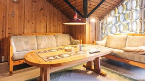 A wooden interior with a sofa, a table, and a patterned wall. - 4 Star Holiday Home in Rodby (Rodby)