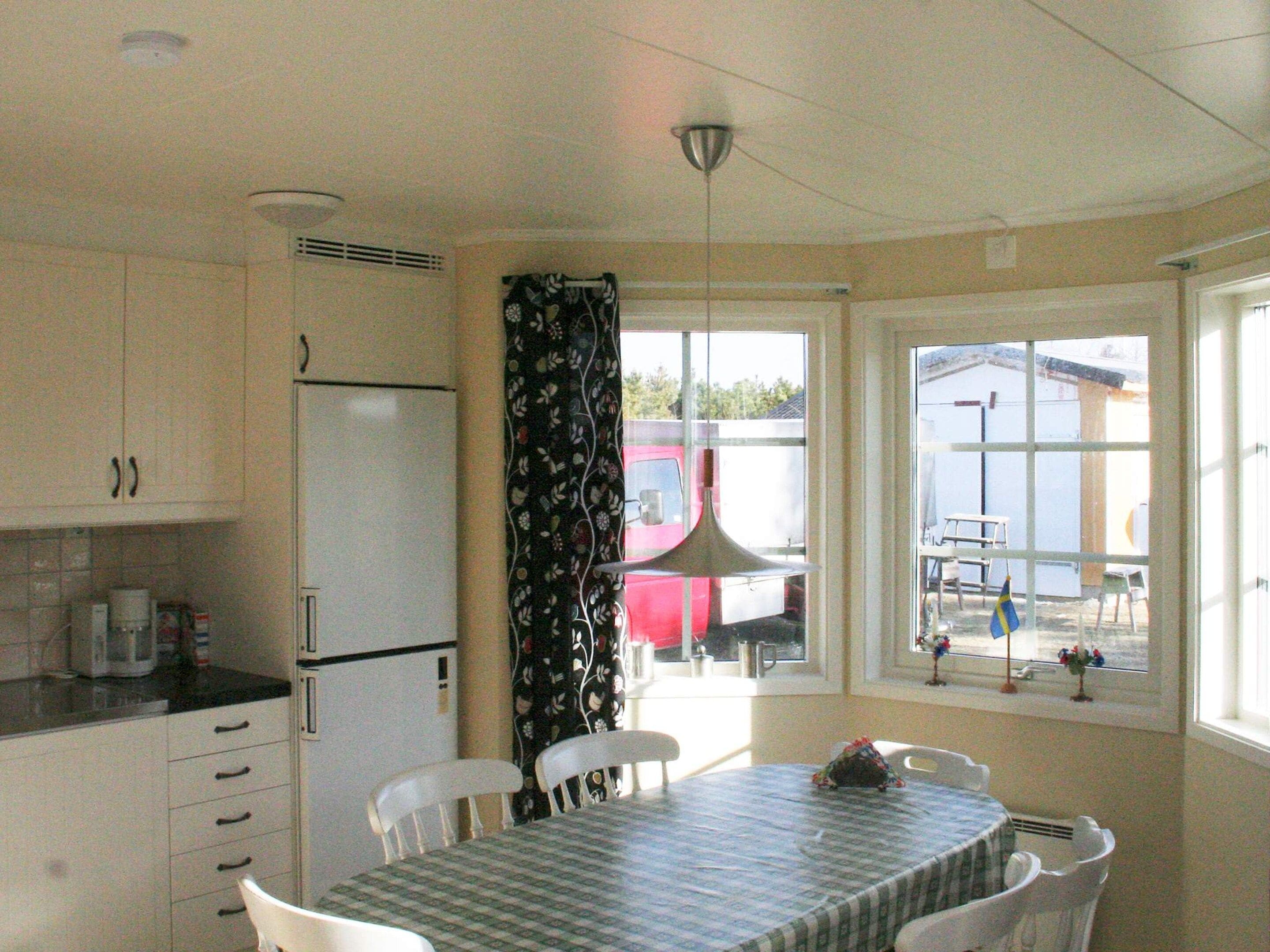 A compact kitchen with a refrigerator, a dining table with chairs, and a window with a view of the outside.