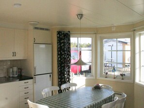 A compact kitchen with a refrigerator, a dining table with chairs, and a window with a view of the outside.