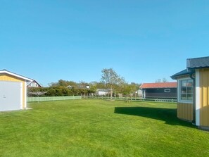 A residential property with a well-maintained lawn, a small shed, and a house with a red roof.