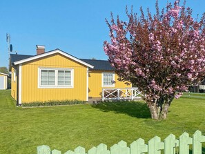 Keltainen talo, jossa on valkoinen ikkuna ja valkoinen aita edessä.