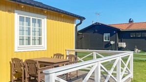 Un bâtiment jaune avec une fenêtre blanche et une terrasse dotée d’une balustrade blanche.