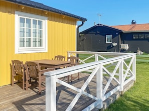 A yellow building with a white window and a deck with a white railing. - 4 Person Holiday Home in Tvaaker (Tvaaker)