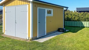 Un petit abri de plain-pied, doté d’un toit à deux versants, d’une porte blanche et d’une fenêtre.