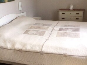 A bed with a white cover and a decorative pillow.