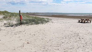 A beach with a lifeguard stand and a picnic table.