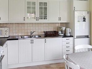 A kitchen with white cabinets, a sink, a coffee maker, and a refrigerator.