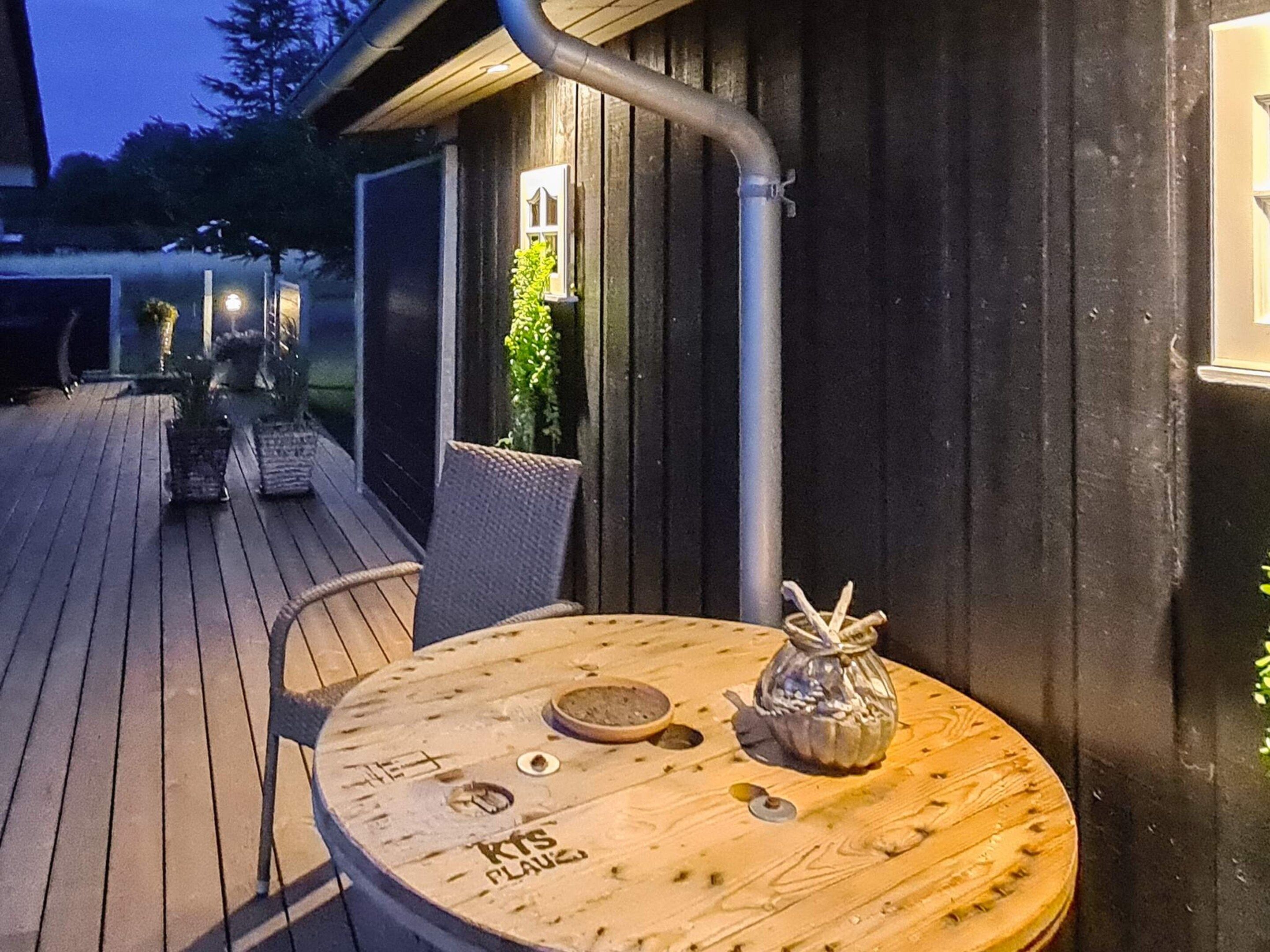 A wooden deck with a round table, chairs, and a small decorative item.