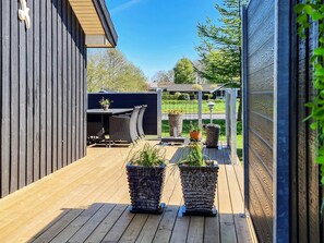 Eine Holzterrasse mit Gartenmöbeln und Kübelpflanzen.