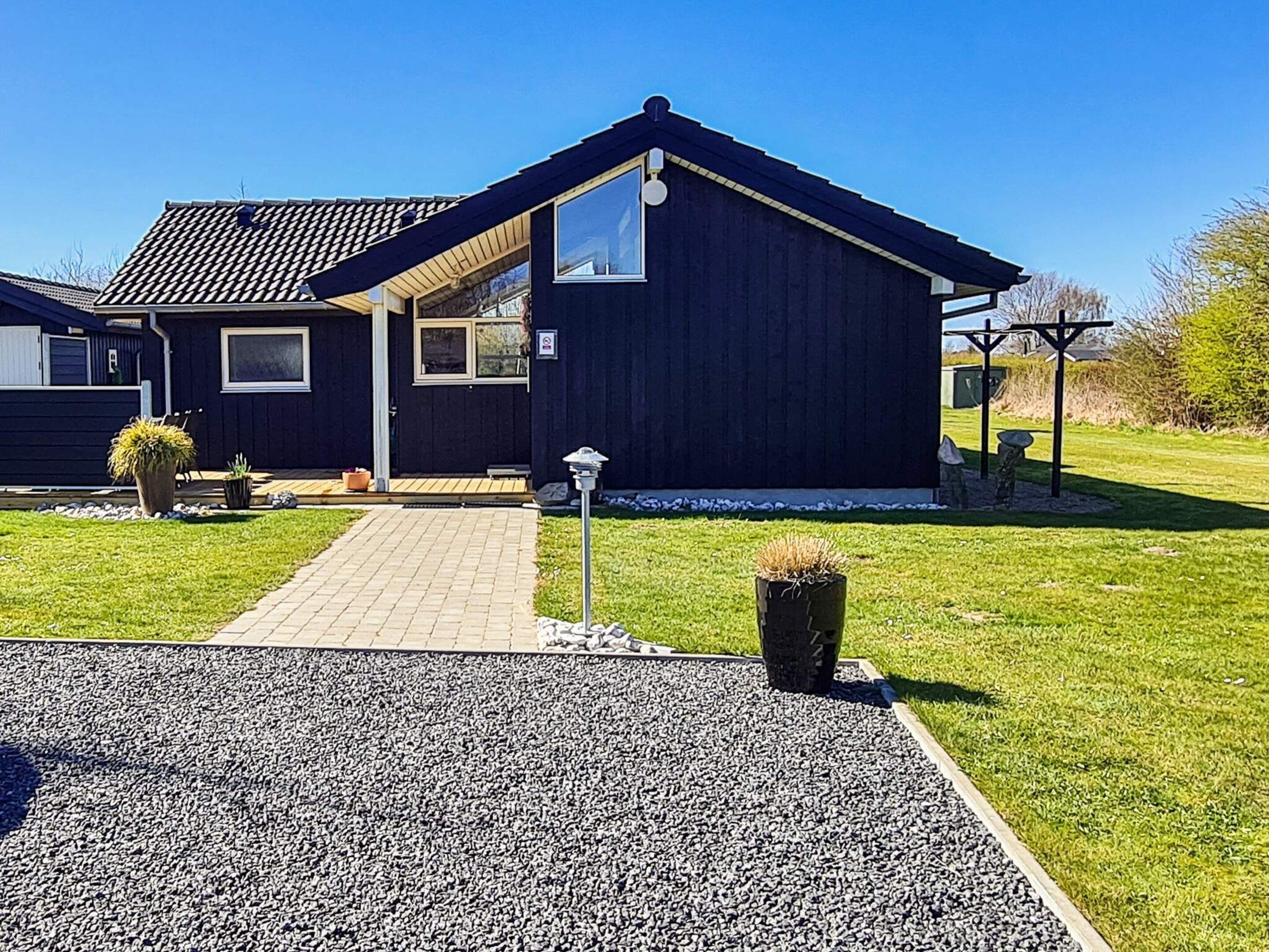 A modern house with a dark exterior, a paved driveway, and a well-maintained lawn.