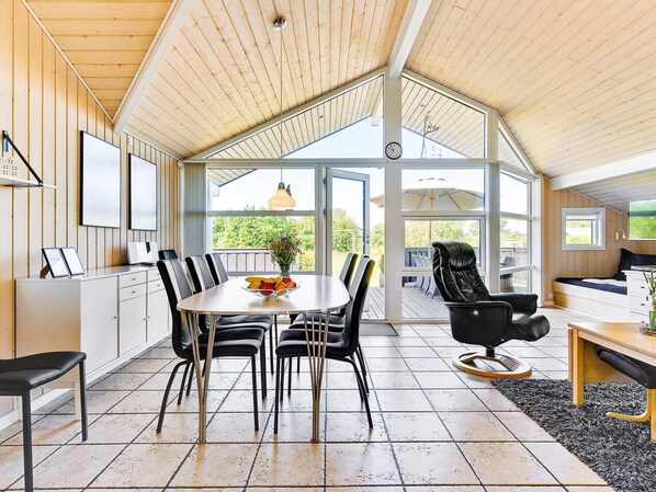 A modern interior with a dining area, a seating area with a sofa, and a bed.