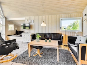 Ein modernes Wohnzimmer mit einer Couch, einem Esstisch und einem Fernseher.