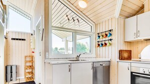 A modern kitchen with white cabinets, a Bosch dishwasher, an LG oven, and a window with a view of greenery. - 4 Star Holiday Home in Nordborg (Nordborg)