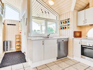A modern kitchen with white cabinets, a Bosch dishwasher, an LG oven, and a window with a view of greenery. - 4 Star Holiday Home in Nordborg (Nordborg)
