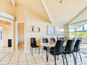 A modern interior with a wooden ceiling, a dining area with black chairs, and a table with fruit.
