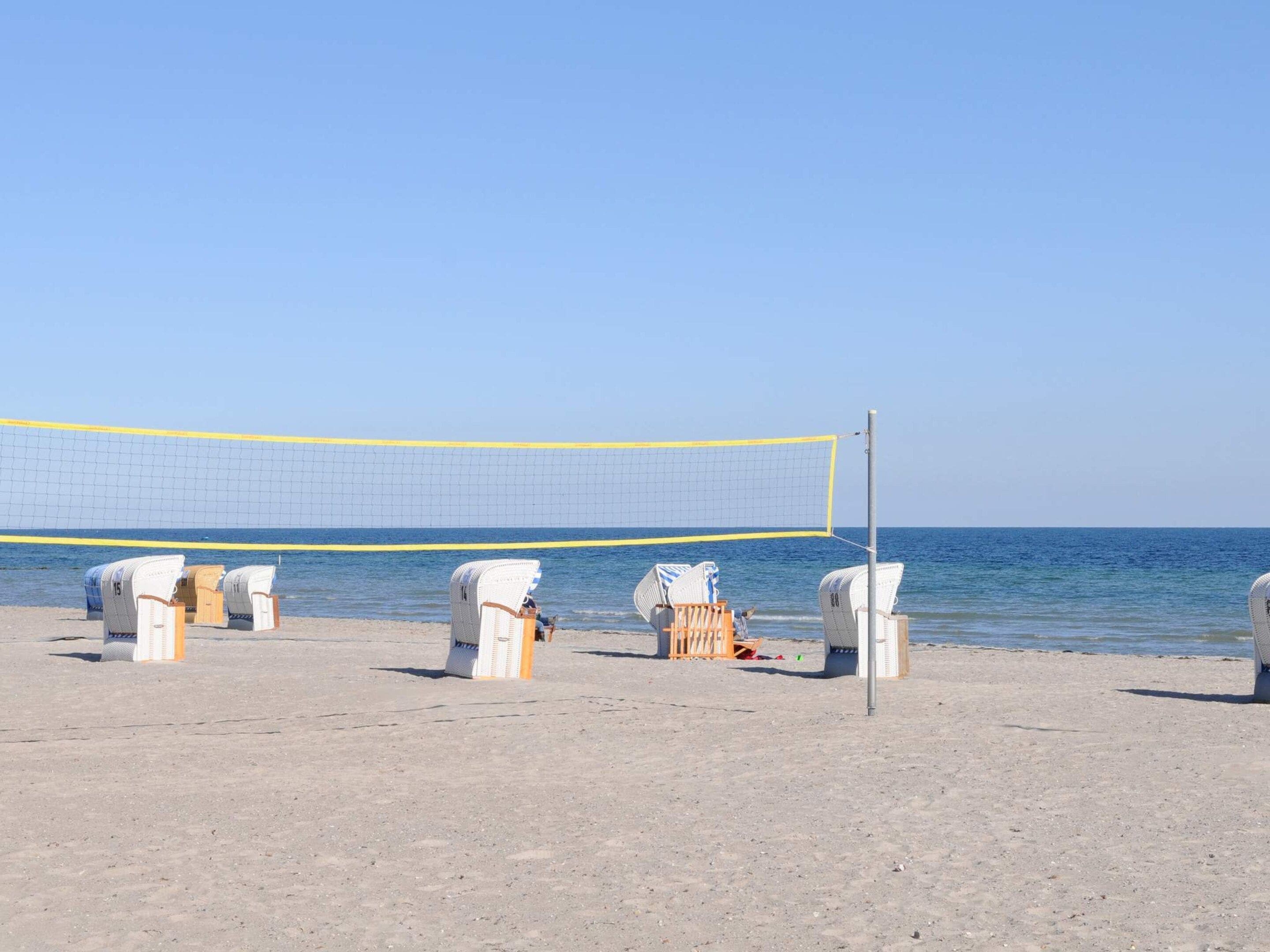 A beach volleyball net with chairs and a volleyball net post.