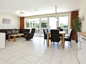 A modern living space with a sofa, dining table, chairs, and a potted plant.
