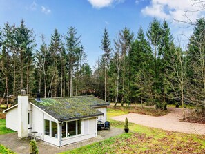 A small, single-story house with a sloped roof, surrounded by a dense forest. - 4 Person Holiday Home in Ans By (Ans)