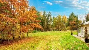 Ein Haus mit Rasen und Bäumen in Herbstfarben.