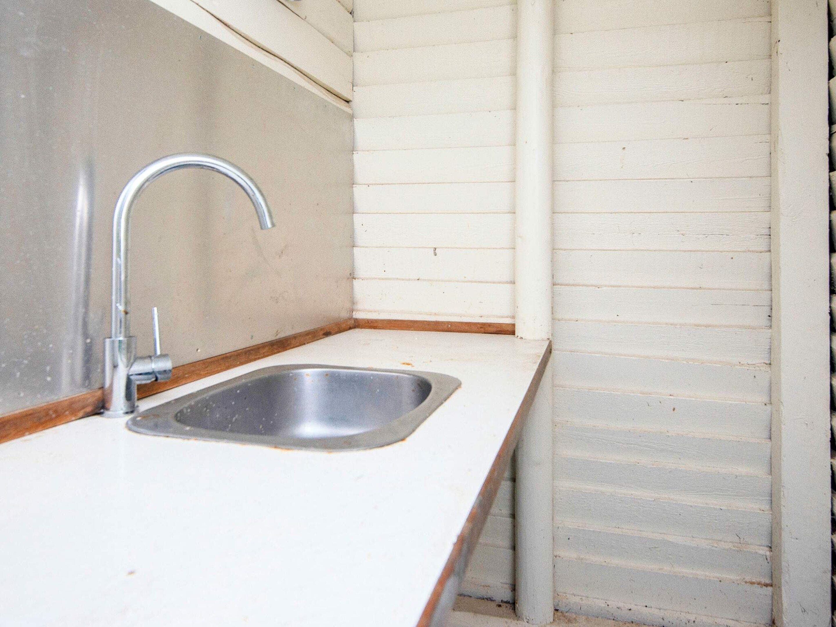 A small kitchen with a single stainless steel sink and a faucet.
