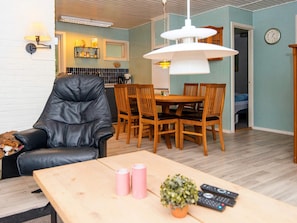 A living room with a leather chair, wooden dining table, and a hanging light fixture. - 4 Person Holiday Home in Ans By (Ans)