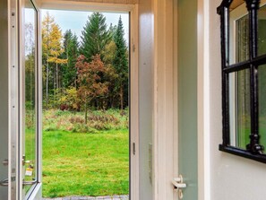 A door leading to a grassy area with trees, a window on the right, and a door handle. - 4 Person Holiday Home in Ans By (Ans)