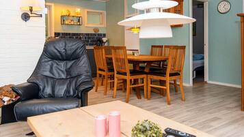Una sala de estar con un sillón de cuero, una mesa de comedor de madera y una lámpara colgante.