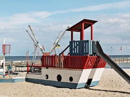 A beach play structure with a slide and climbing nets.