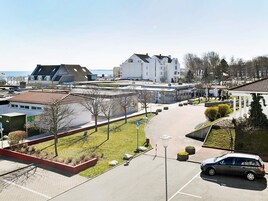 A parking area with a car, a building with a sloped roof, and a clear sky.